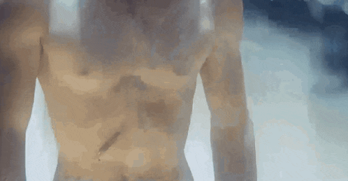 a man without a shirt is standing in a pool of water and looking at the camera .