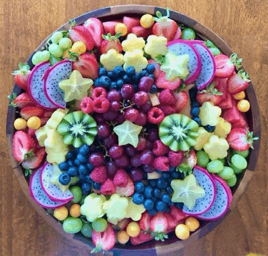 a wooden bowl filled with a variety of fruits and berries