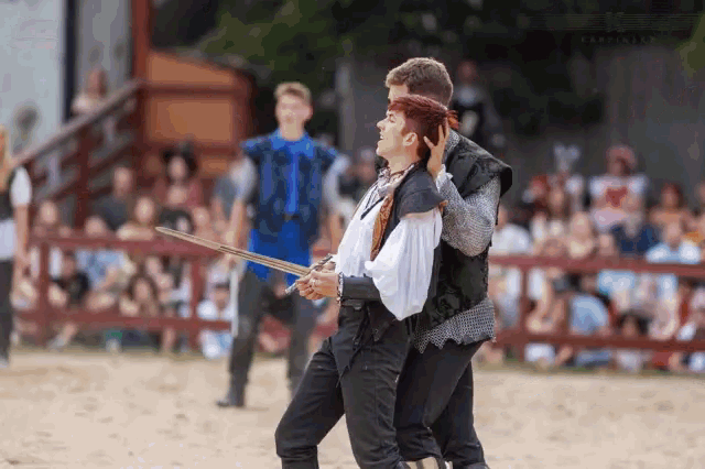 a man and a woman are holding swords in front of a crowd at a medieval event