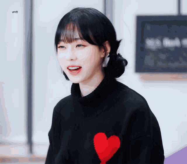 a girl in a black sweater with a red heart on it