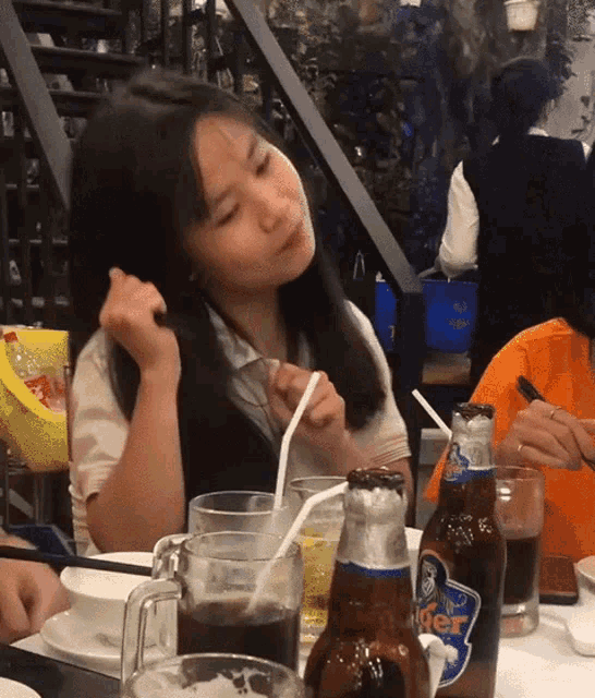 a woman sitting at a table with tiger beer bottles