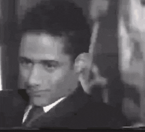 a man in a suit and tie is making a funny face in a black and white photo .