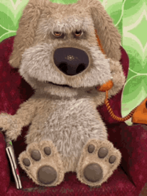 a stuffed animal dog is sitting in a chair talking on a phone