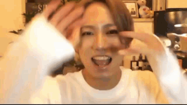 a man in a white shirt is making a funny face with his hand .