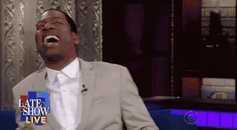 a man in a suit and tie is laughing on a late show live show .