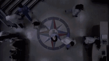 a group of people are standing around a compass on the floor in a dark room .