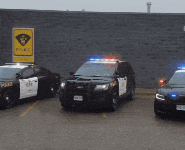 three o.p.p. police cars are parked in front of a brick building