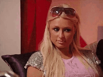 a blonde woman wearing sunglasses is sitting on a couch .