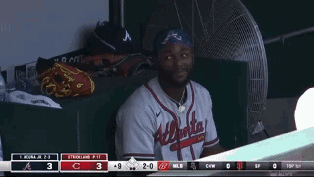 a man wearing an atlanta jersey sits in a dugout