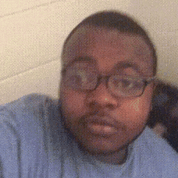 a man wearing glasses and a blue shirt looks at the camera