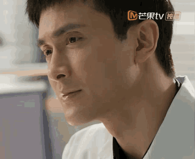 a close up of a man 's face with a chinese tv logo above his ear