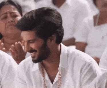 a man with a beard is wearing a white shirt and smiling