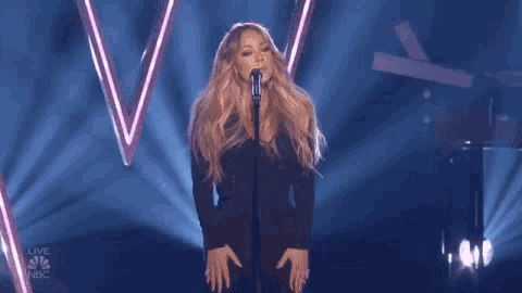 a woman singing into a microphone with nbc written on the bottom
