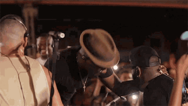 a man in a hat is kissing another man on the cheek in front of a crowd of people .