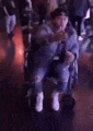 a man in a wheelchair is sitting in a dark room holding a drink .