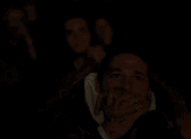 a man is covering his face while watching a movie in a theater