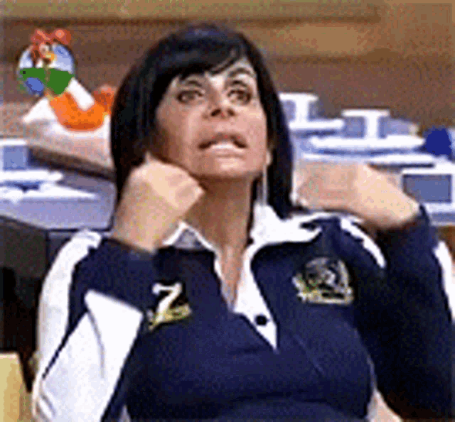 a woman in a blue and white jacket is sitting at a table with her hands on her face .