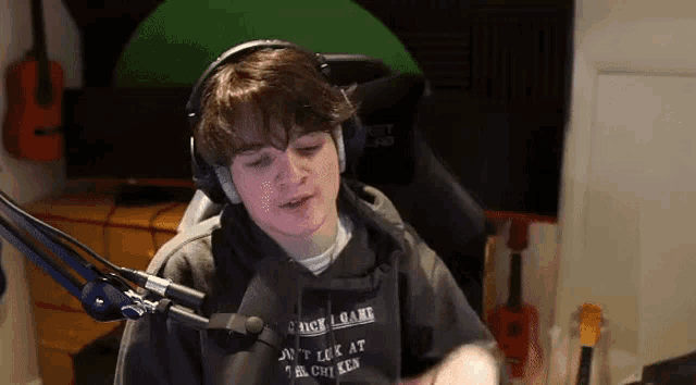 a young man wearing headphones is sitting in front of a microphone in a room .