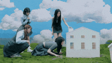 a group of girls are kneeling down in front of a white house