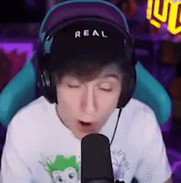 a boy wearing headphones and a hat is talking into a microphone .
