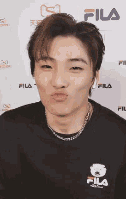 a man wearing a black fila shirt is making a funny face