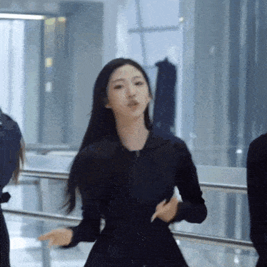 a girl in a black dress is dancing in a room