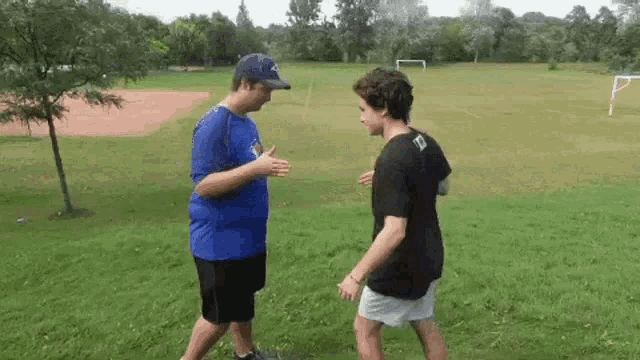 two young men are standing next to each other in a field .