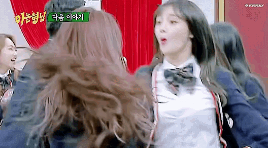 a group of girls are standing next to each other in a room . one of the girls is wearing a school uniform .