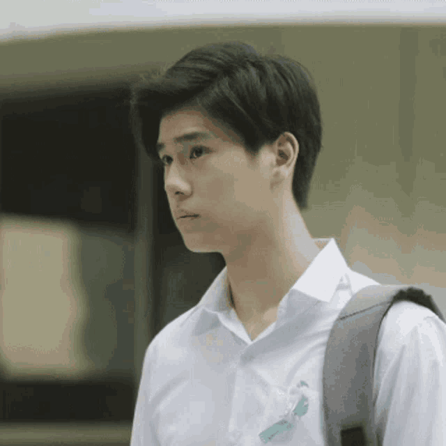 a young man in a white shirt with a backpack on his back