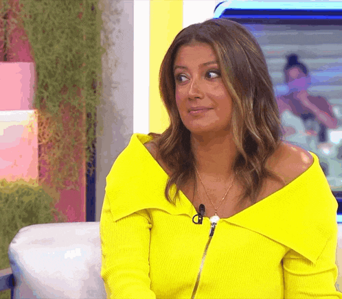 a woman wearing a yellow off the shoulder top with a microphone on her neck