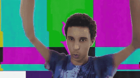 a man in a blue tie dye shirt is dancing in front of a colorful background .