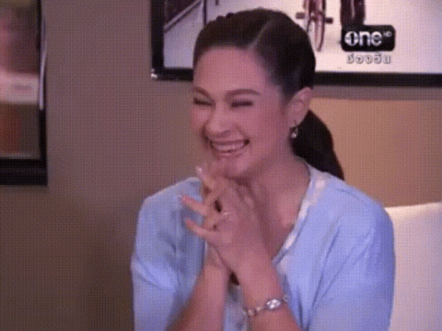 a woman in a blue shirt is laughing in front of a sign that says one on it