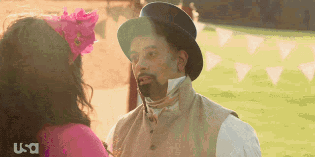 a man in a top hat is looking at a woman in a pink dress with usa written on the bottom