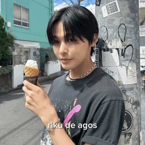 a person wearing a riku de agos t-shirt is holding a cone of ice cream