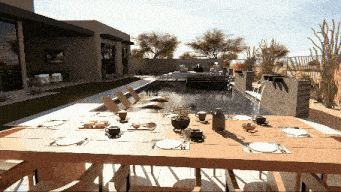 a table with plates and utensils sits in front of a large pool