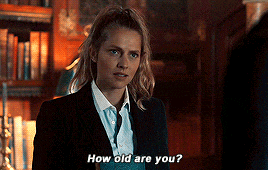 a woman in a suit is talking to a man in a library and says how old are you ?