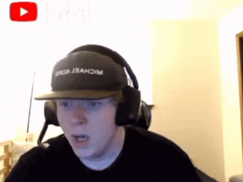 a man wearing a michael kors hat and headphones looks surprised