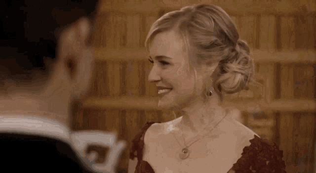 a woman in a red dress is smiling while looking at a man in a suit .