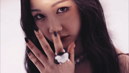 a close up of a woman 's face with a ring on her finger