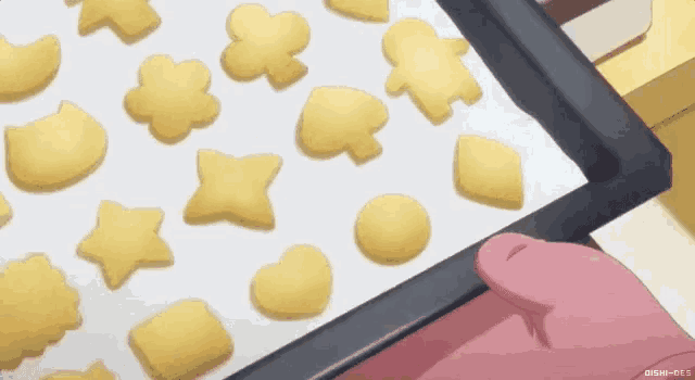 a person is holding a tray of cookies in different shapes