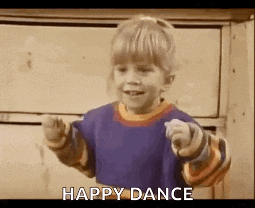 a little boy is dancing and pointing at the camera while wearing a blue shirt .