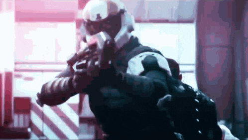 a soldier in a helmet is holding a gun in a room .