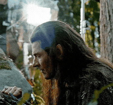 a man with long hair is holding a sword in his hand .