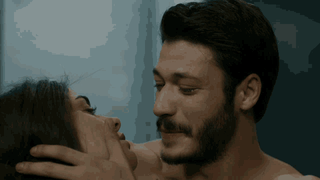 a man with a beard is kissing a woman on the cheek