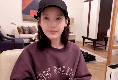 a woman wearing a black hat and a purple sweatshirt that says new balance