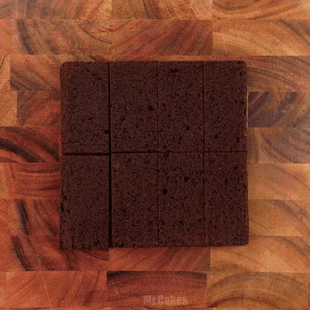 a wooden cutting board with a square of brownies on it