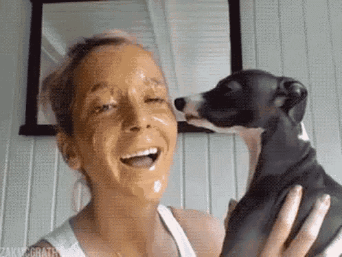 a woman is holding a dog with a face mask on her face .