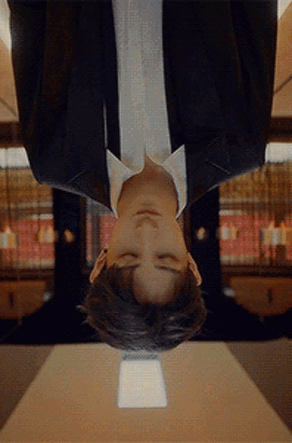 a man in a suit and white shirt is upside down with his eyes closed