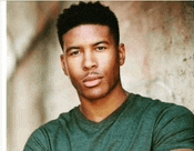 a young man in a green t-shirt is standing in front of a wall .
