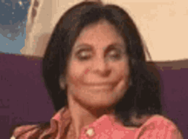a woman is sitting on a purple couch and smiling .
